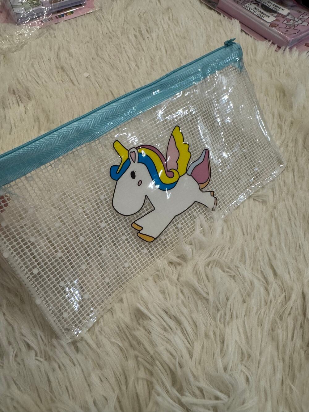 Clear unicorn pencil case with blue zipper and cartoon unicorn graphic